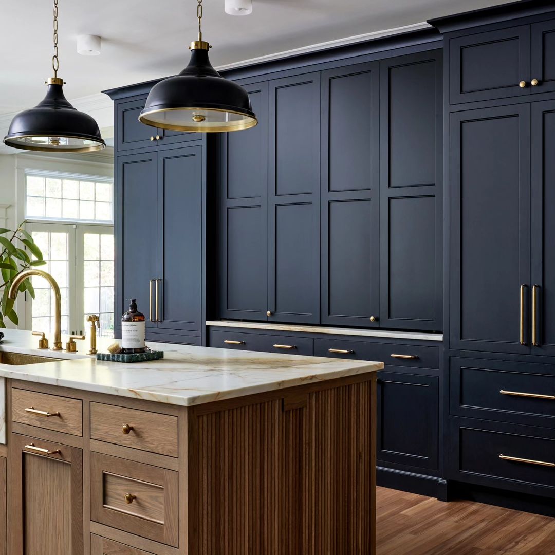 A sophisticated kitchen featuring deep blue cabinetry, contrasting wooden textures, and brass hardware accents.