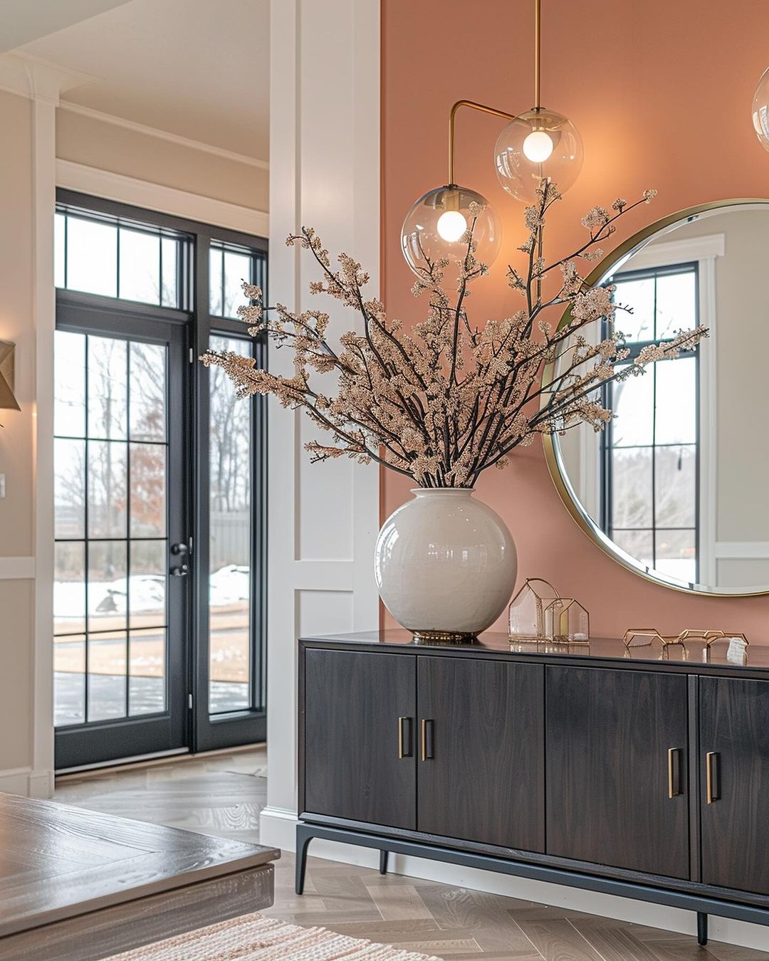 A chic entryway featuring a two-tone cabinet and large spherical pendant lights.