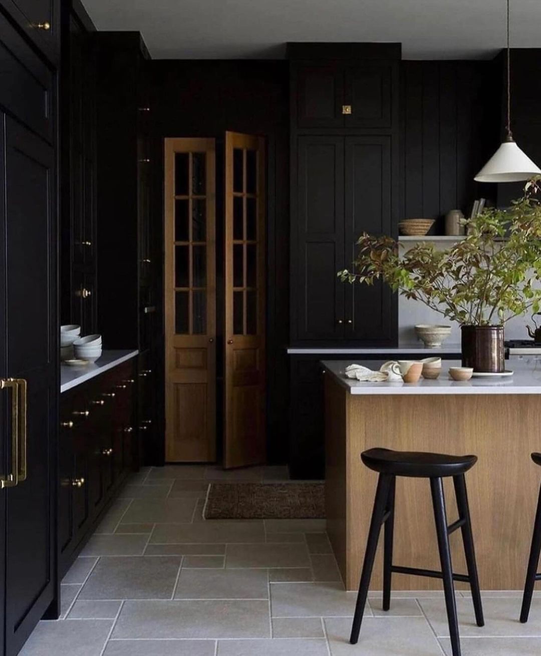 A chic and modern kitchen featuring a striking contrast with dark cabinetry and light countertops, complemented by a wooden island and sleek bar stools.