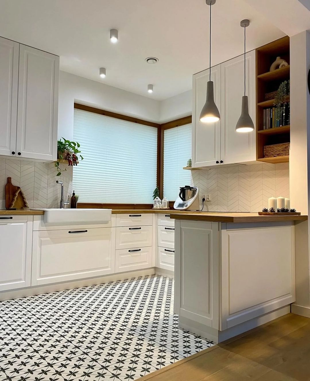 A chic and functional kitchen featuring black-and-white patterned floor tiles, white cabinetry, and wood accents.