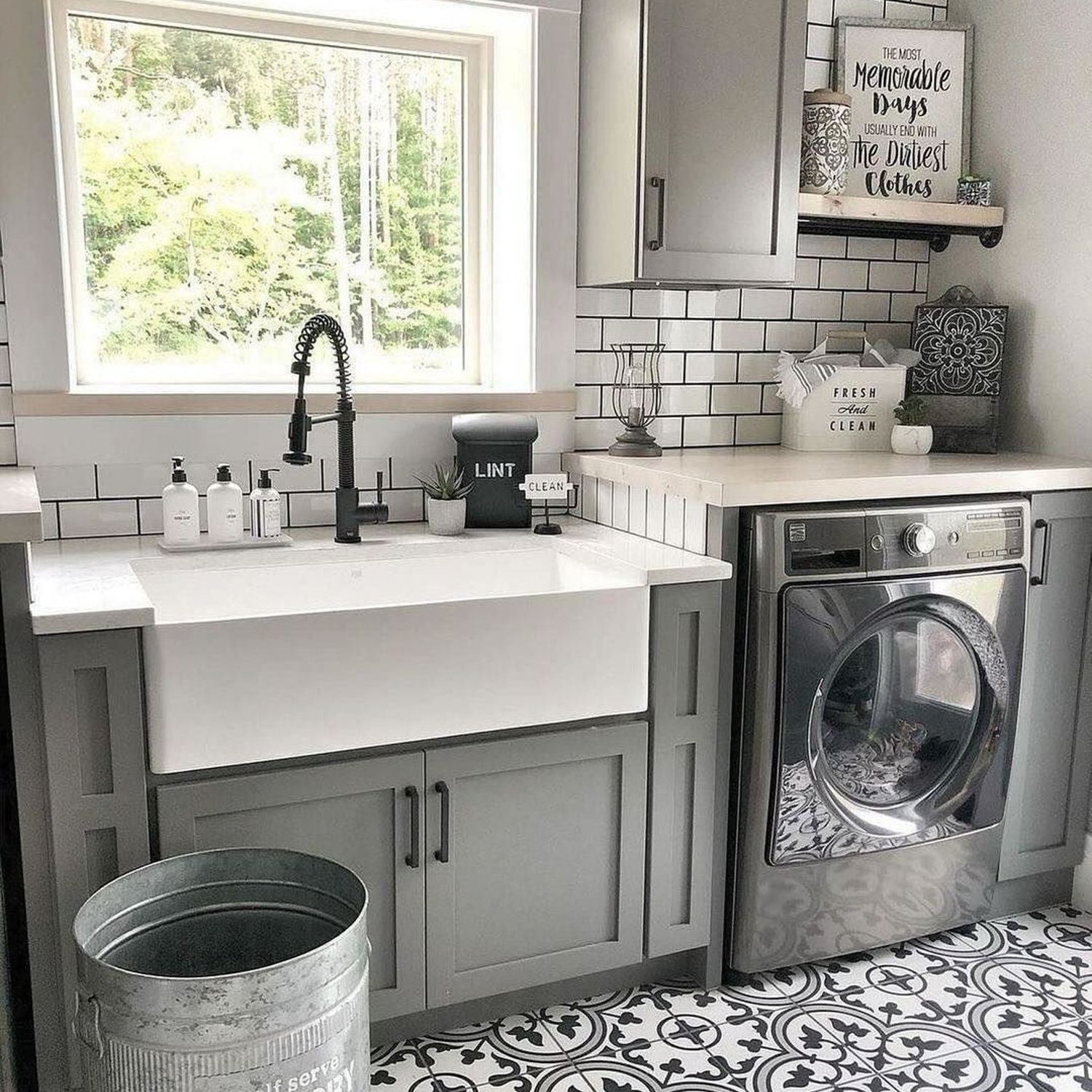 A sleek and modern laundry room featuring white cabinetry, stainless steel appliances, and a bold patterned floor tile.