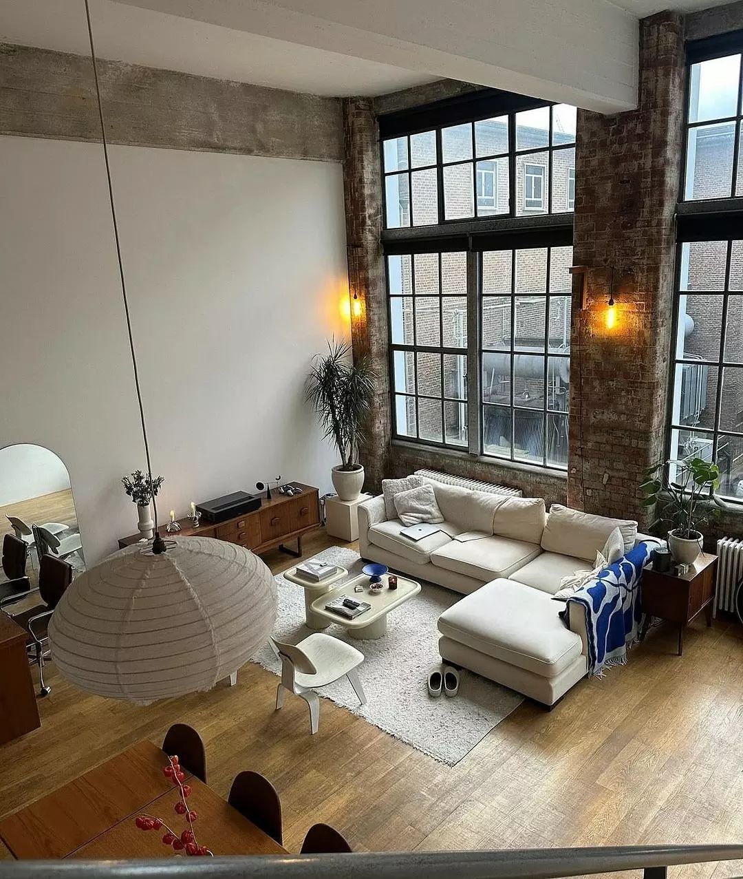 A chic urban loft living room featuring exposed brick and large windows