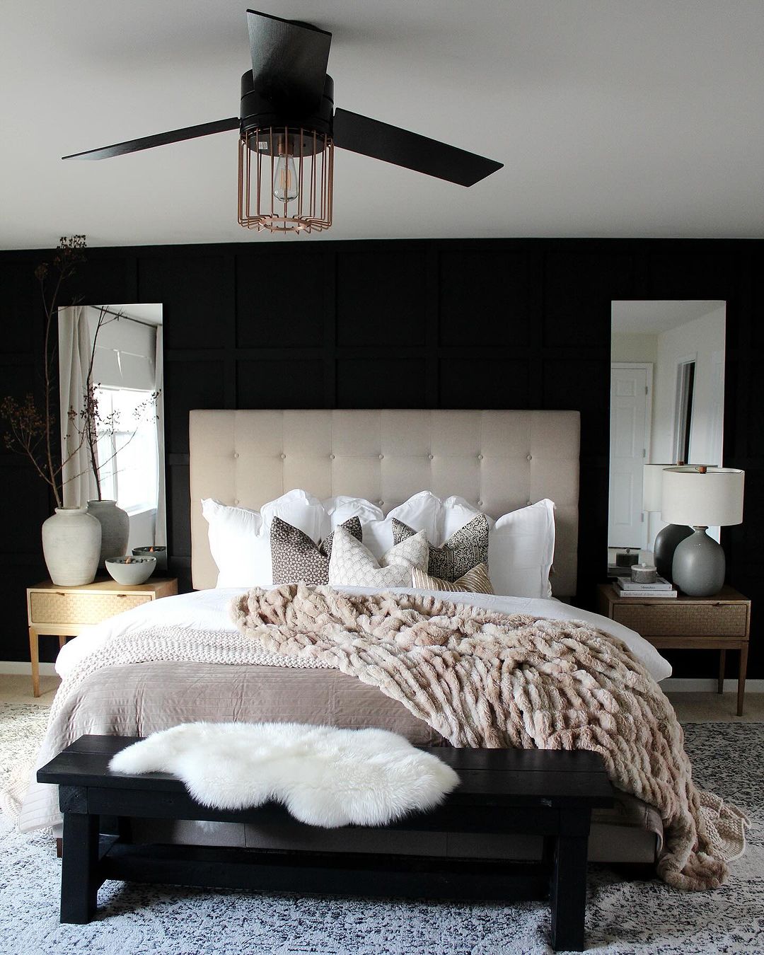 A stylish and modern bedroom with bold black accent wall and chic neutral-toned bedding