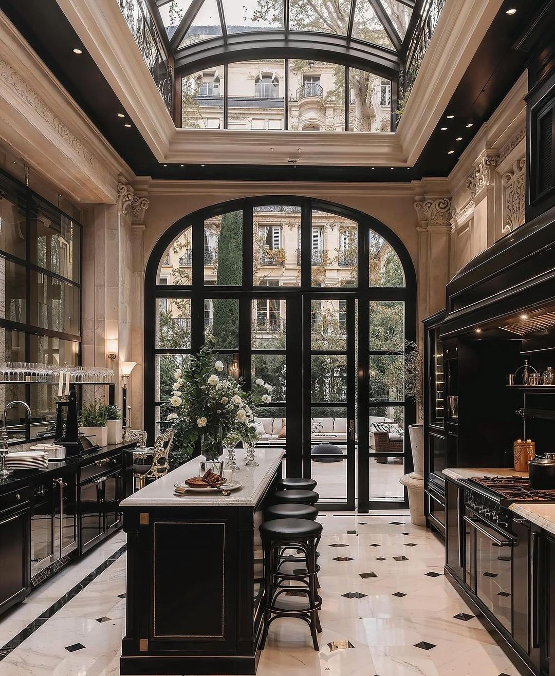 A sophisticated Parisian-style kitchen featuring black cabinetry, marble countertops, and herringbone flooring