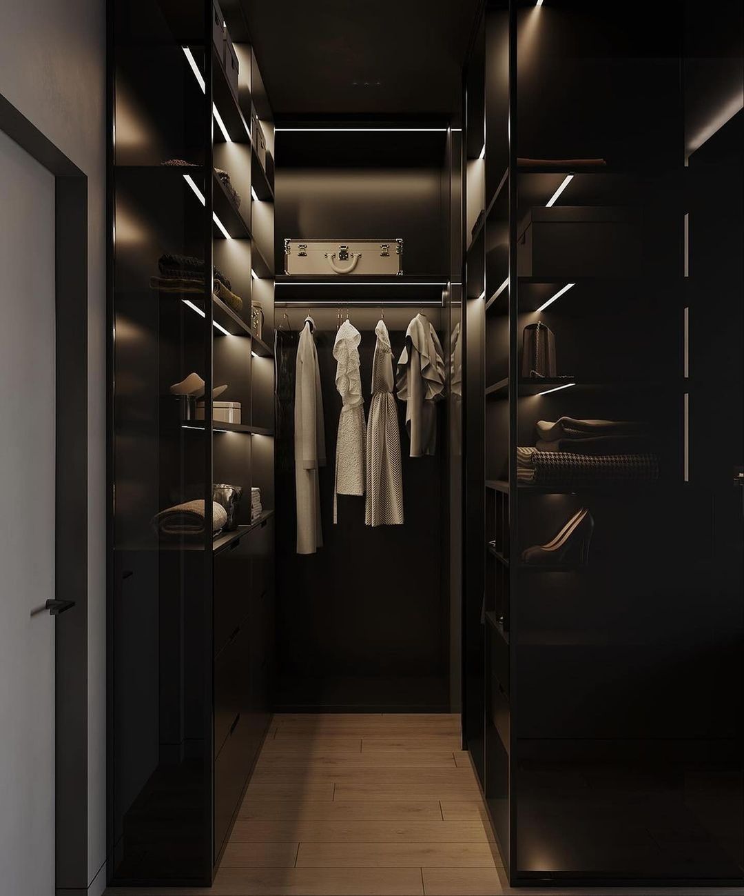 A chic and modern walk-in closet with sleek black shelves, integrated lighting, and a selection of stylish hanging garments.