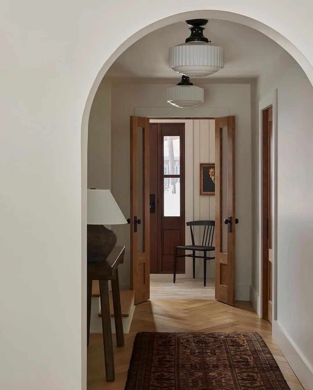 A serene archway frames a wooden door adding warmth and texture to this minimalist hallway