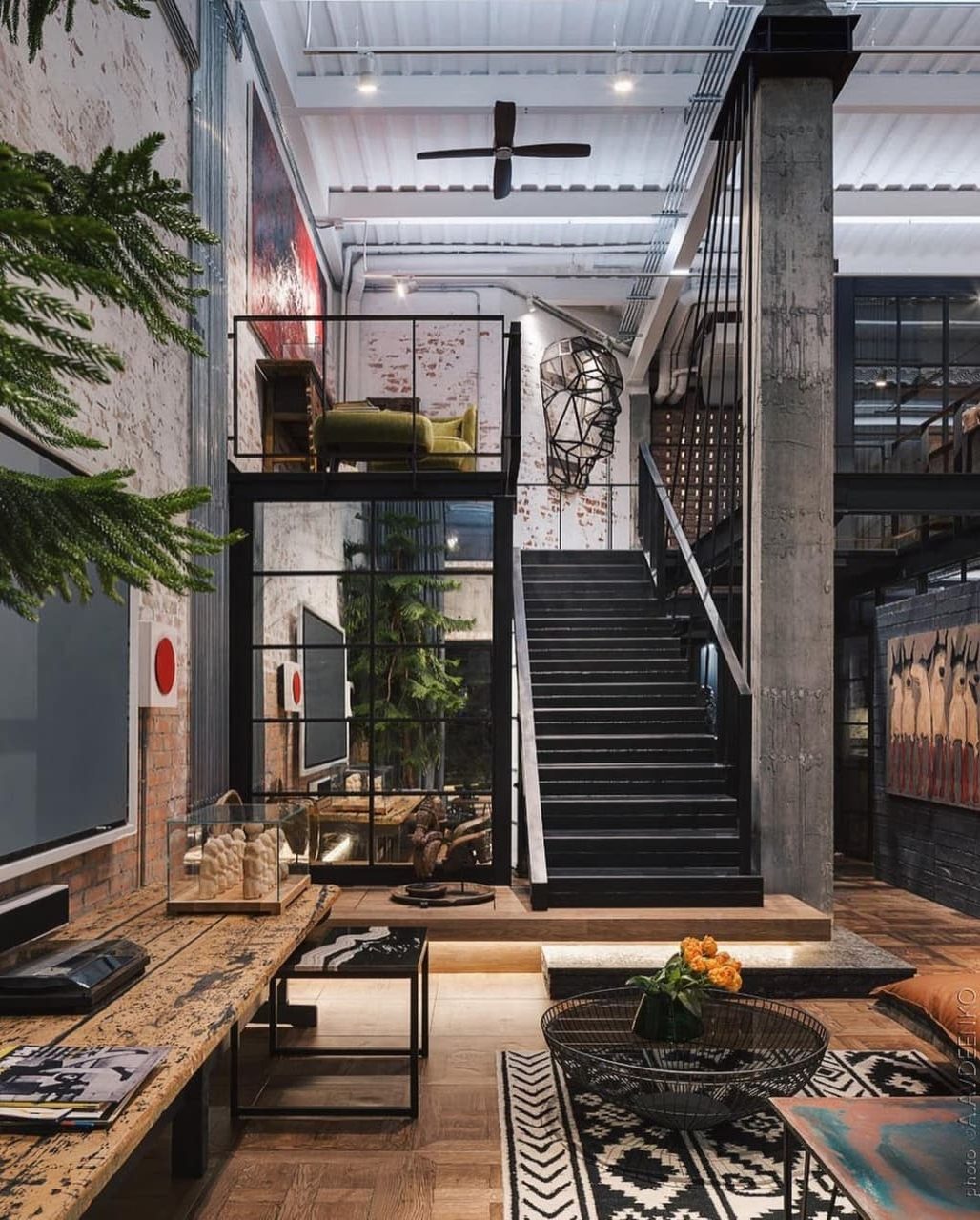 An eclectic urban loft featuring a black staircase, exposed brick walls, and a mix of industrial and rustic decor elements