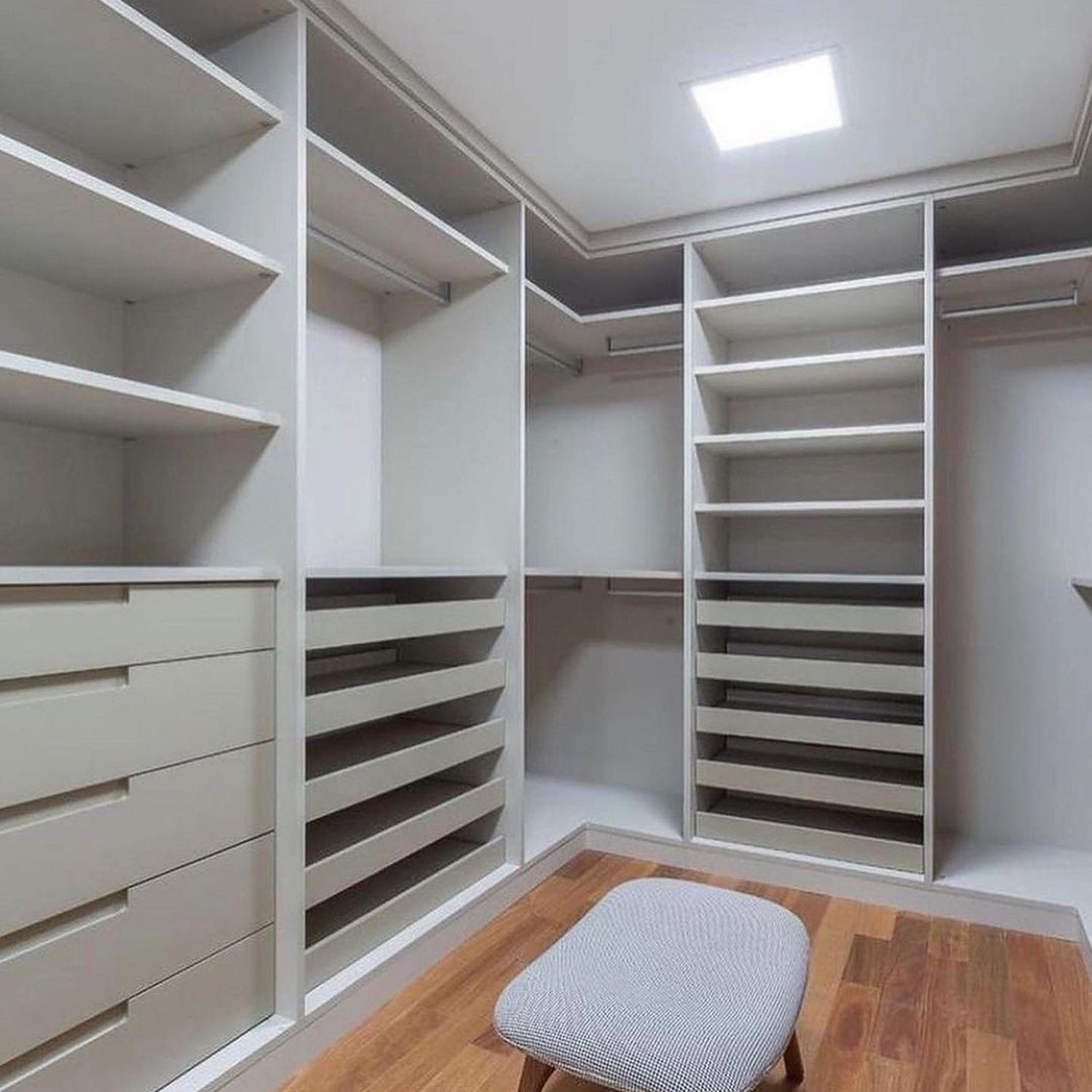 Elegantly designed walk-in closet with ample shelving and a seating stool