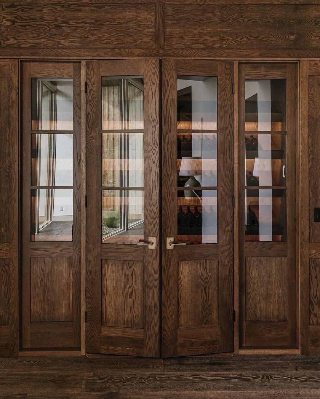 Stunning walnut-paneled glass doors revealing a glimpse into a modern wine room