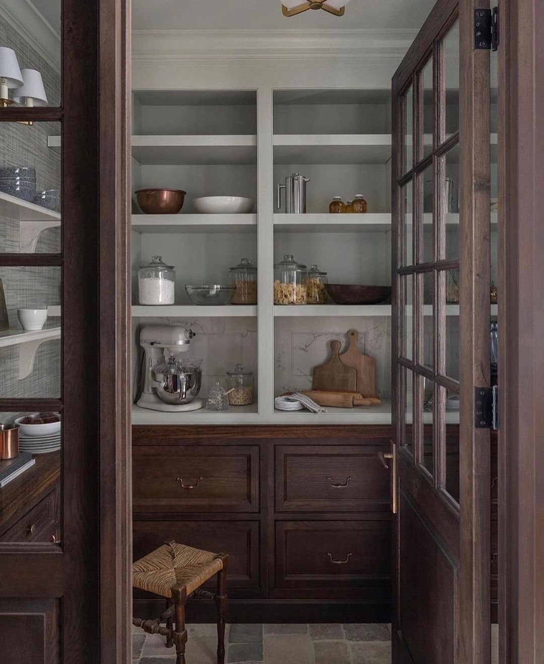 A meticulously organized pantry with glass-front cabinets showcasing a collection of kitchenware